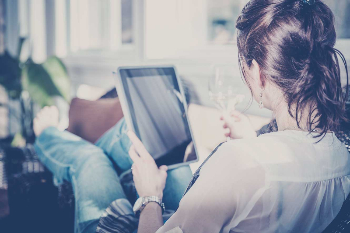 Woman sitting in a chair looking at a tablet