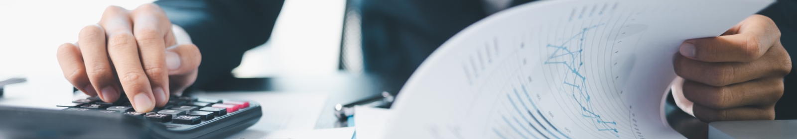 professional using a calculator and flipping through sheets of paper