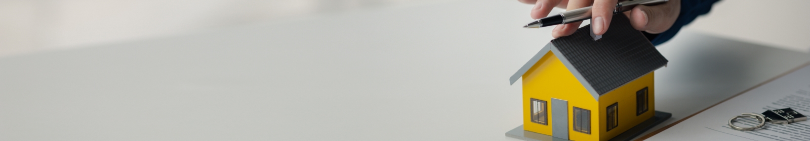 hand with pen touching a miniature home