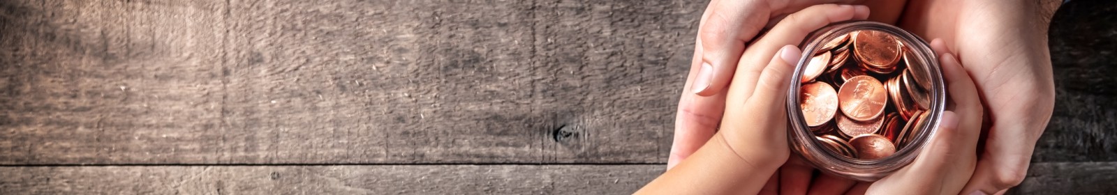 adult and baby's hands grasping a jar full of pennies