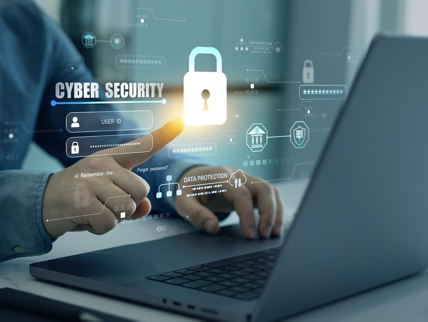 professional using a laptop pointing at a cyber security lock floating in front of them