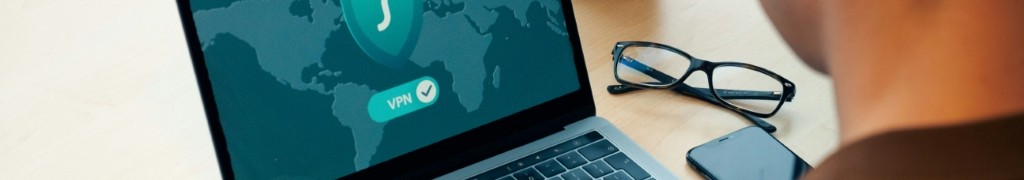 man staring at a laptop with a cybersecurity symbol and VPN lock on screen