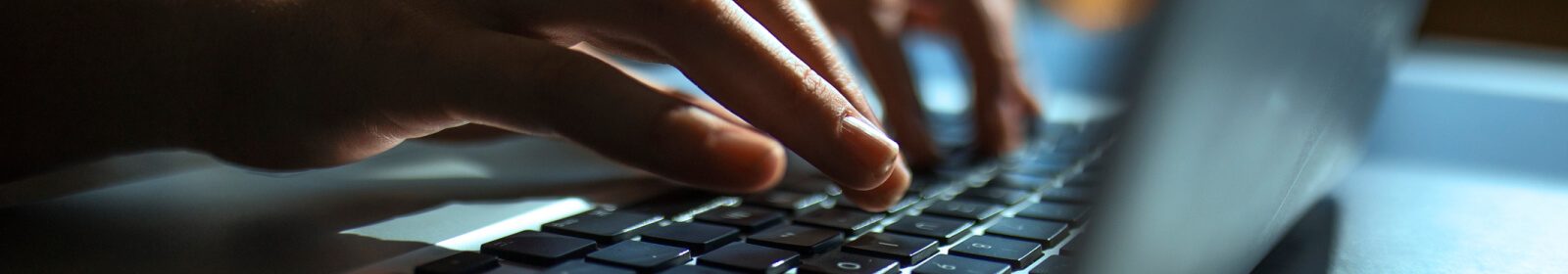 hands typing on a laptop keyboard