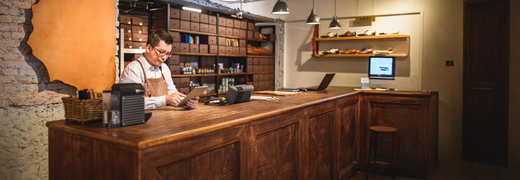 professional staring at an electronic tablet in his shoe workshop business