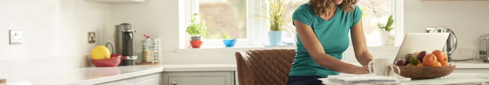 woman working on a laptop in her kitchen at home