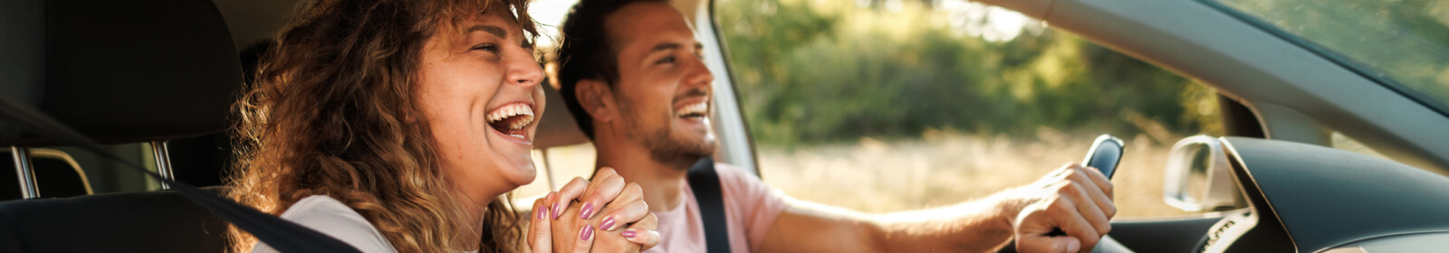 young man and woman smiling and holding hands in a car
